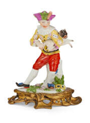 AN ORMOLU-MOUNTED MEISSEN PORCELAIN COMMEDIA DELL'ARTE FIGURE OF HARLEQUIN HOLDING A PUG AS A HURDY-GURDY