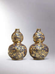 AN EXCEPTIONALLY RARE AND EXQUISITE PAIR OF BLUE-GROUND GILT-DECORATED ‘MELON AND VINE’ DOUBLE GOURD-FORM VASES