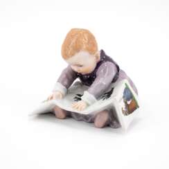 PORCELAIN FIGURINE OF A SMALL CHILD WITH PICTURE BOOK