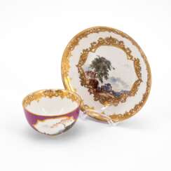 PORCELAIN TEA BOWL AND SAUCER WITH PURPLE GROUND AND LANDSCAPE CARTOUCHES