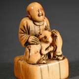 Sehr altes Elfenbein Netsuke "Mann mit Hund auf Sockel sitzend", bernsteinfarbene Patina, Japan um 1700/1720, H. 4,2cm, Provenienz: Norddeutsche Sammlung, Genehmigung nach Art. 10d VO (EG 338/97) liegt vor, kein Export außerhalb der EU - photo 2