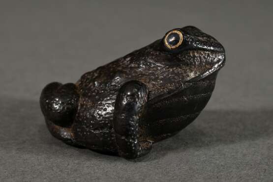 Ebenholz Netsuke "Großer, kräftiger Frosch" mit aus Messing und schwarzem Horn doppelt eingelegten Augen, kleines und großes Himotoshi, L. 4,8cm, Provenienz: Norddeutsche Sammlung - photo 1