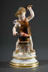 Meissen Figur „Amor als Schmied“ auf profiliertem Rundsockel mit Terrainplinthe, polychrom staffiert, Entw.: Heinrich Schwabe, um 1890, zeitnahe Ausführung, Modellnr.: L114, Bossiernr.: 101, Malernr.: 58 H. 18,8cm