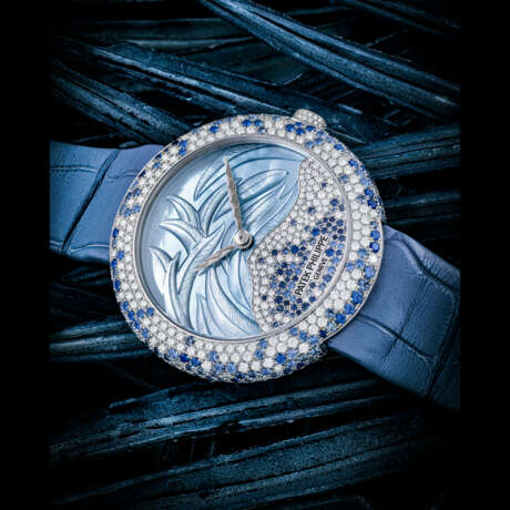 PATEK PHILIPPE. A LADY’S ATTRACTIVE 18K WHITE GOLD, DIAMOND AND BLUE SAPPHIRE SET AUTOMATIC WRISTWATCH WITH HAND-ENGRAVED MOTHER-OF-PEARL DIAL - Foto 1