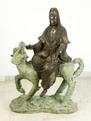 Large Asian bronze group of Guanyin sitting on a fabulous animal, on naturalistic style integrated oval base