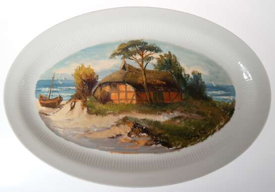 Porzellan-Platte, ovaler Spiegel bemalt von Hermann Vaegler (1910 Greifswald -1992 Wolgast) "Fischerkaten am Strand", signiert r.u., ges. 24x36 cm - фото 1