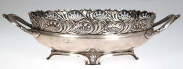Jugendstil-Schale, 800er Silber, oval, mit floral durchbrochenem Rand, auf 4 Füßen, 2 reliefierte Handhaben, 1 kl. Delle, 539 g, 9,5x35,5x18,5 cm