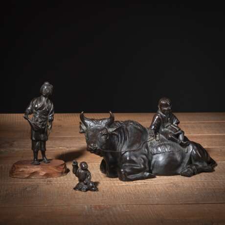 Drei Okimono aus Bronze: ruhender Büffel mit jungem Hirten auf Rücken, stehende Bäuerin und sitzender Knabe mit erhobenem Arm - photo 1