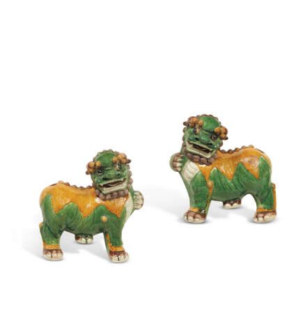 A PAIR OF GREEN, YELLOW AND AUBERGINE-GLAZED BISCUIT BUDDHIST LIONS - photo 1