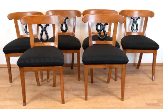 Biedermeier-Tisch mit 6 Stühlen, Kirschholz, um ca. 1820, Tisch mit sechseckiger Mittelsäule, mit schwarz gefärbtem Birnbaumholz, Tischplatte in massiv Buche erneuert, Tischplatte mit Riß, Dm. 117 cm, H. 77,5 cm, bei den Stühlen ist der Sitz in … - photo 1