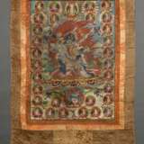 Thangka „Dharmapāla Mahākāla (?) vor Flammenaureole (blaue Körperfarbe und drei Augen) mit hellblauer Paretra mit Schädelschale und Hackmesser in yab-yum, darüber Buddha Amitāyus in Regenbogen, darunter weiterer Dharmapā… - Foto 4
