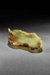 A WELL-CARVED GREEN AND BROWN JADE LOTUS LEAF-FORM WASHER