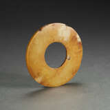 A MOTTLED RUSSET AND PALE-GREENISH-BUFF JADE DISC - Foto 1