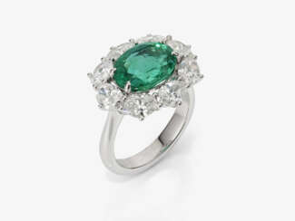 An entourage ring with an emerald and diamonds.