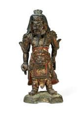A PARCEL-GILT AND PAINTED BRONZE FIGURE OF A STANDING GUARDIAN