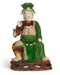 A GREEN, YELLOW AND AUBERGINE-GLAZED BISCUIT FIGURE OF A GUANDI