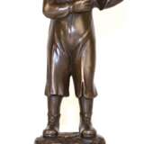 Bronze-Figur "Junge zündet sich im Schutz seines Hutes eine Zigarette an", Nachguß, braun patiniert, bezeichnet "Nick", Gießerplakette "JB Paris", auf rundem, schwarzem Steinsockel, Ges.-H. … - фото 1