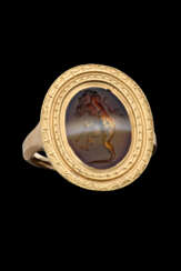 A EUROPEAN BANDED AGATE RINGSTONE WITH CUPID HOLDING A MASK