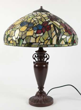 Tischlampe im Tiffanystil, 2. Hälfte 20. Jh., 2-flammig, bronzierter Metallfuß in Vasenform auf rundem Stand, Schirm aus farbigem Kunstglas mit Floraldekor, H. 57 cm, Dm. 43 cm - Foto 1