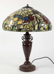 Tischlampe im Tiffanystil, 2. Hälfte 20. Jh., 2-flammig, bronzierter Metallfuß in Vasenform auf rundem Stand, Schirm aus farbigem Kunstglas mit Floraldekor, H. 57 cm, Dm. 43 cm