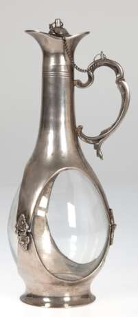 Karaffe mit Metall-Montierung, um 1930, gebauchter Klarglaskorpus, Metallummantelung mit Henkel und Stopfen an Kette, H. 31,5 cm - Foto 1