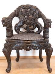 Sessel mit reichem Schnitzdekor mit Drachenmotiven, schwarz gefaßt, Krallenfüße, Armlehnen in Drachenköpfen endend, 86x60x42 cm