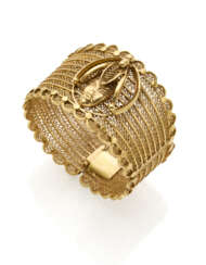 Yellow gold openwork bangle bracelet with centerpiece accented with mask, g 70.23 circa, h cm 4.0, diam. cm 6.0 circa circa.