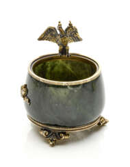 FABERGE' | Nephrite and partly gilded metal container accented with a spread winged eagle, medal on the base, g 178.42 circa, h cm 6.70, diam. cm 5.60 circa circa. Signed Fabergé in cyrillic, russian assay and goldsmith marks. (slight defects).
