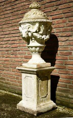 Guss- oder Sandstein Deckelvase mit Widderkopf auf hohem eckigem Postament nach altem Vorbild, bez.: "Decor Garden", 20.Jh., 153x42x42cm, Witterungsspuren - фото 1