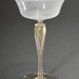 Zarter venezianischer Champagnerkelch mit Fadenglas Kuppa über hohem Stiel mit eingeschmolzenen Goldfolien, Anfang 20.Jh., H. 18cm, Ø 11,9cm - Maintenant aux enchères