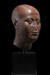 AN EGYPTIAN RED QUARTZITE HEAD OF A PRIEST
