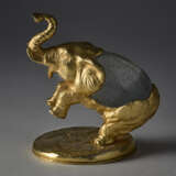 "Elefante" | Lost-wax sculpture of the series "Piccoli animali". 1970s. Hand-chiselled and gilded metal, Murano crystal glass egg by Barovier e Toso. Signed by incussion at the base. Metal label under the base. (10.5x14.5x12 cm.) | | Provenance | - photo 1