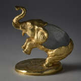 "Elefante" | Lost-wax sculpture of the series "Piccoli animali". 1970s. Hand-chiselled and gilded metal, Murano crystal glass egg by Barovier e Toso. Signed by incussion at the base. Metal label under the base. (10.5x14.5x12 cm.) | | Provenance | - photo 2