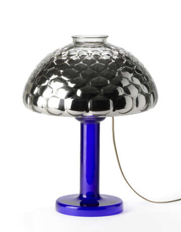 Table lamp model "Nina". Produced by Fontana Arte,, 1981. Transparent blue blown glass frame, adjustable silvered optical glass light diffuser. Bearing label. (h 50 cm.) | | Literature | G. Gramigna, Repertorio del design italiano 1950-2000 per l'a - Foto 4