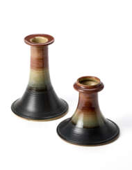Two candle-holders. Execution by Ceramica Arcore,, 1970s. Lathe-turned stoneware partially glazed in black-cream and brown. (h max 15 cm.)