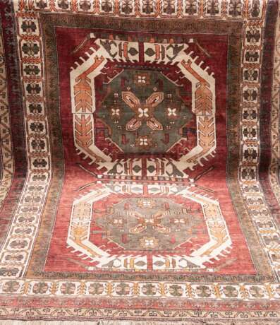 Teppich, auf rostbraunem Grund grünlich ornamental gemustert, Rand mit Riß und Loch, Fransen unterschiedlich lang, 245x172 cm - photo 1