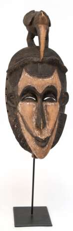 Stammes-Maske mit Vogel als Bekrönung, Afrika, Holz geschnitzt, farbig gefaßt, H. 47 cm, auf Ständer, Ges.-H. 68 cm - photo 1