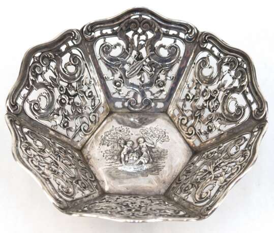 Durchbruchschälchen, 800er Silber, 8-kantiger Korpus floral durchbrochen, mittig reliefierte figürliche Szenen mit Putten in Landschaft, gewellter Reliefrand, 162 g, H. 6,5 cm, Dm. 14,7 cm - фото 1