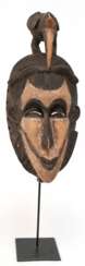 Stammes-Maske mit Vogel als Bekrönung, Afrika, Holz geschnitzt, farbig gefaßt, H. 47 cm, auf Ständer, Ges.-H. 68 cm