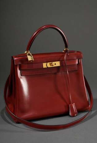 Hermès "Kelly Bag 28", 1993, bordeauxfarbenes Kalbsleder mit goldfarbener Hardware, Schultergurt und Schloss mit 2 Schlüsseln, innen Reißverschluss- und 2 Steckfächer, geprägtes Monogramm "IG", 22x28x… - photo 3