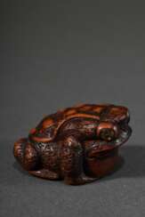 Kleines Buchsbaum Netsuke &quot;Sitzende Kröte&quot; mit eingelegten Augen aus hellem und schwarzem Horn, punzierte und fein gearbeitete Rückenpartie mit Gebrauchspatina, verschieden große Himotoshi, Mitte 19.Jh., L. 3,6…