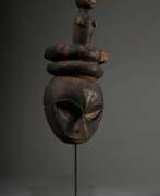 Aperçu. Eket Ogbom Maske mit figürlichem Aufsatz, Nigeria, sichelförmige Augen, Reste von farbiger Bemalung, 42,5x17,5x12cm, mit Ständer, Provenienz: Norddeutsche Privatsammlung ML