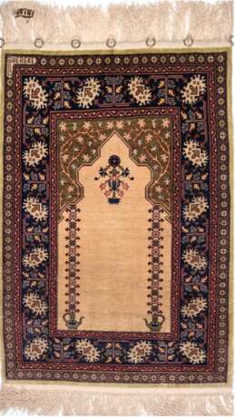 Hereke, Türkei, Seide, signiert und nummeriert, mit Gebetsgiebel, ca.1 Mio Knoten/qm, hellgrundig mit floralen und ornamentalen Motiven in Rot, Blau und Grün, am oberen Rand 7 Messing-Ösen, 76x50 cm (ohne Fransen gemesse… - photo 1