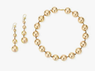 A gold bead necklace and a pair of gold drop earrings. Italy