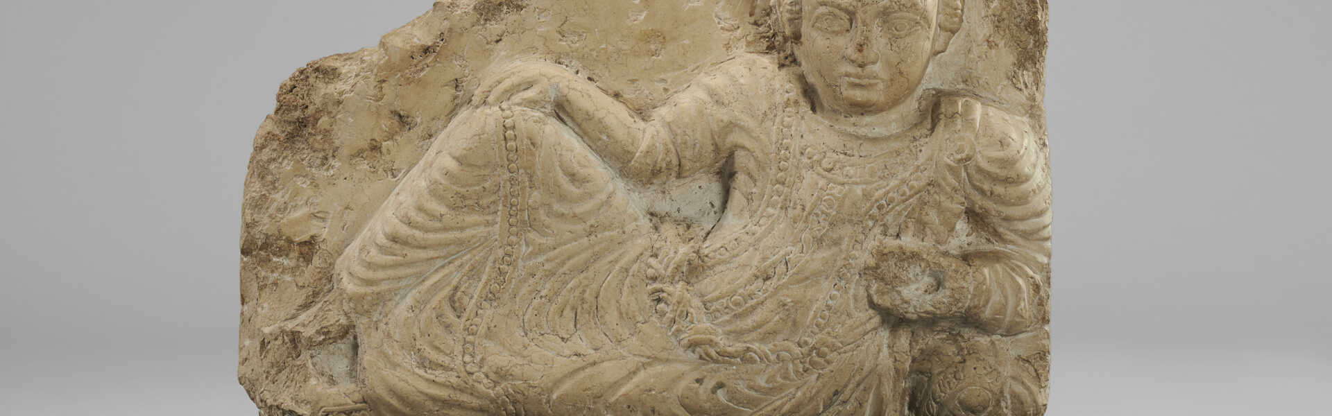 A PALMYRENE LIMESTONE RELIEF WITH A RECLINING MAN