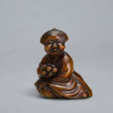 A CARVED WOOD NETSUKE OF A SEATED WOMAN HOLDING BELLS - Foto 1