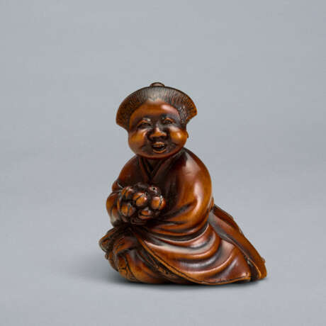 A CARVED WOOD NETSUKE OF A SEATED WOMAN HOLDING BELLS - Foto 1