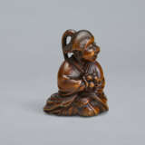 A CARVED WOOD NETSUKE OF A SEATED WOMAN HOLDING BELLS - Foto 2