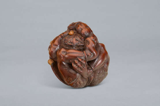 A CARVED WOOD NETSUKE OF A ONI UNDER HAT - фото 2