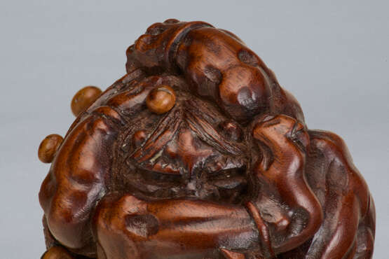 A CARVED WOOD NETSUKE OF A ONI UNDER HAT - фото 3